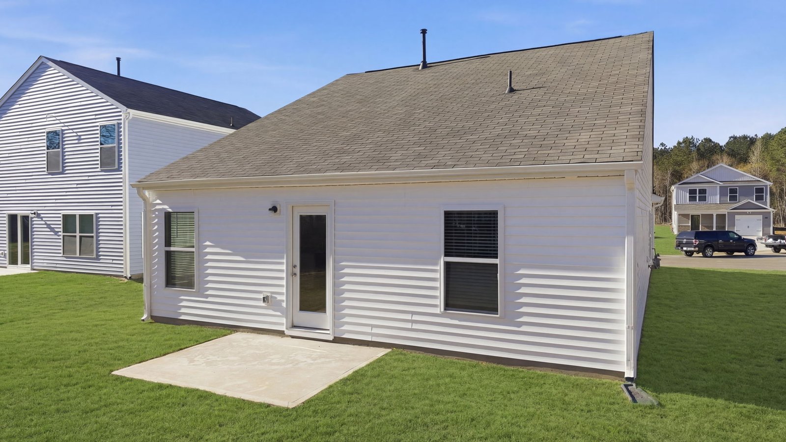 Back of the home with back yard and patio pad