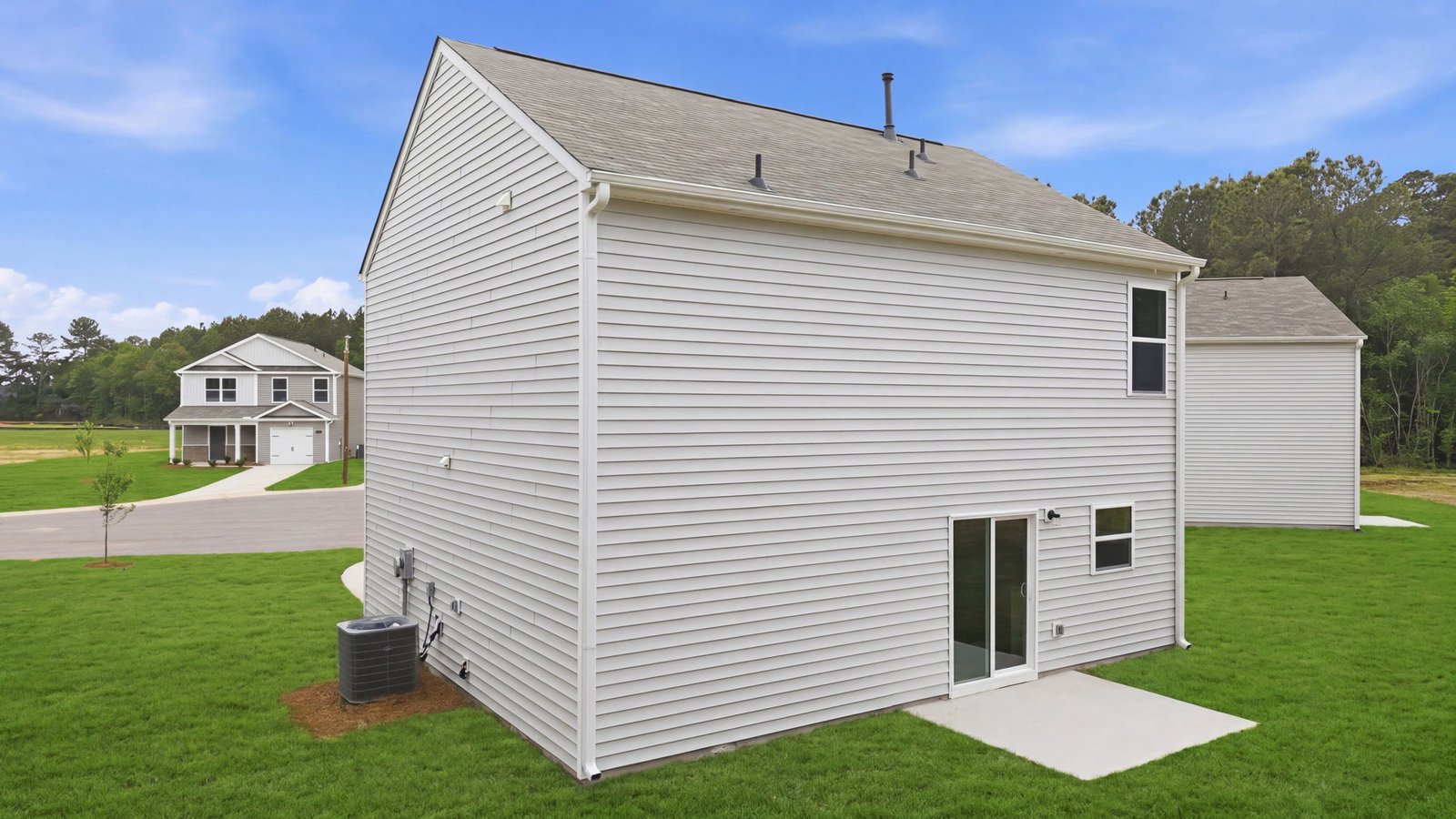 rear view of two story home with vinyl and back patio pad