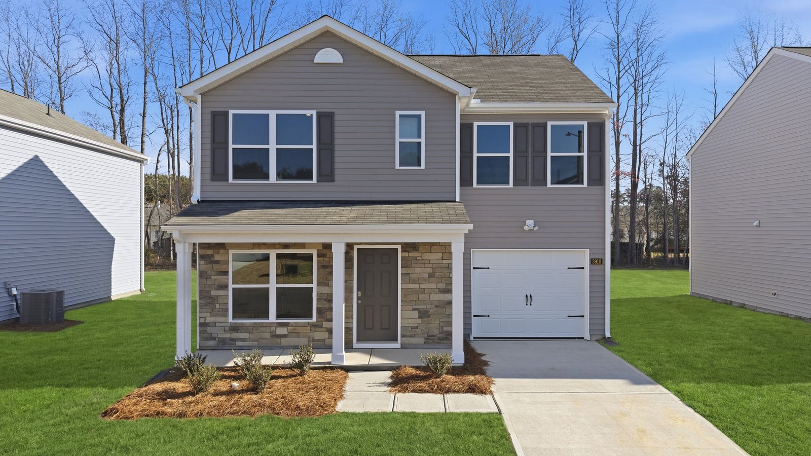 Two story home with brick and tan vinyl with two car garage
