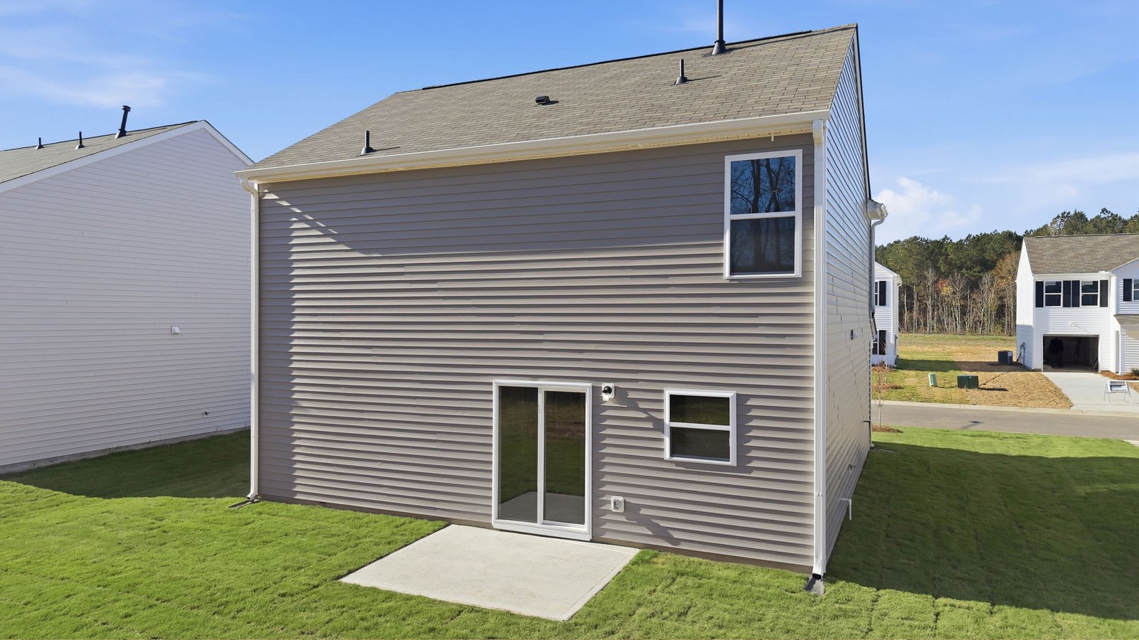 Rear view of back of the two story home with back yard