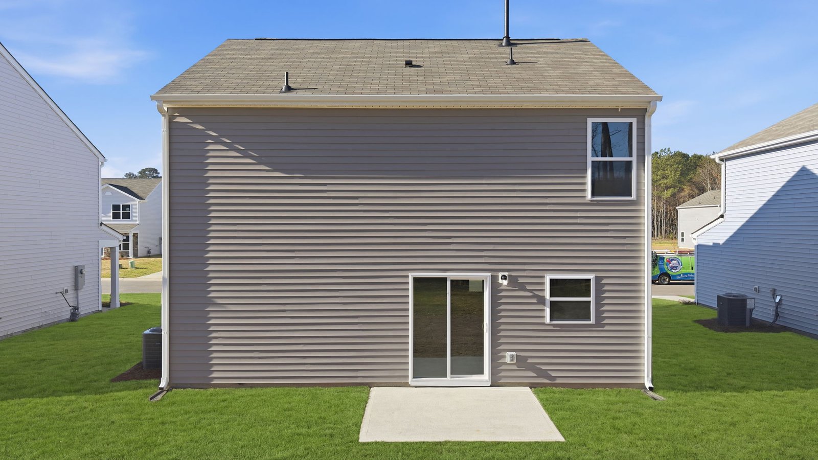 Back of the two story home with sliding glass door from dining area leading onto the back patio
