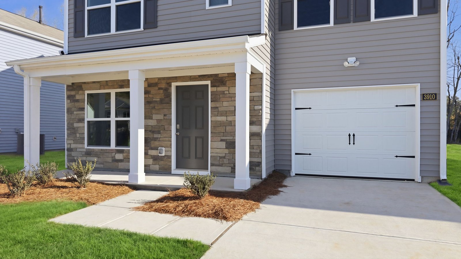 Front porch that is covered with beams and paved sidewalk to main driveway