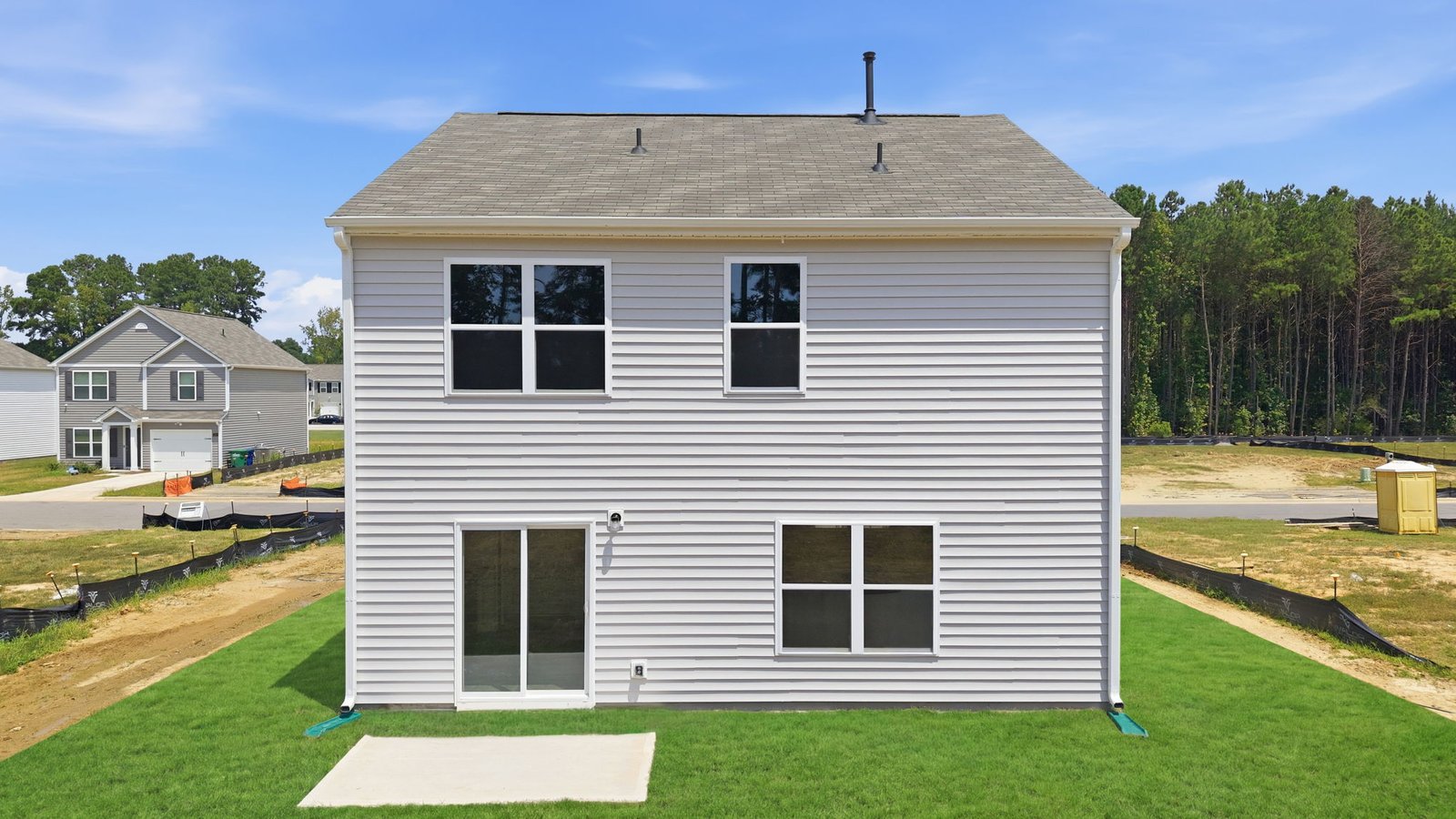 rear view of home with yard and back patio pad