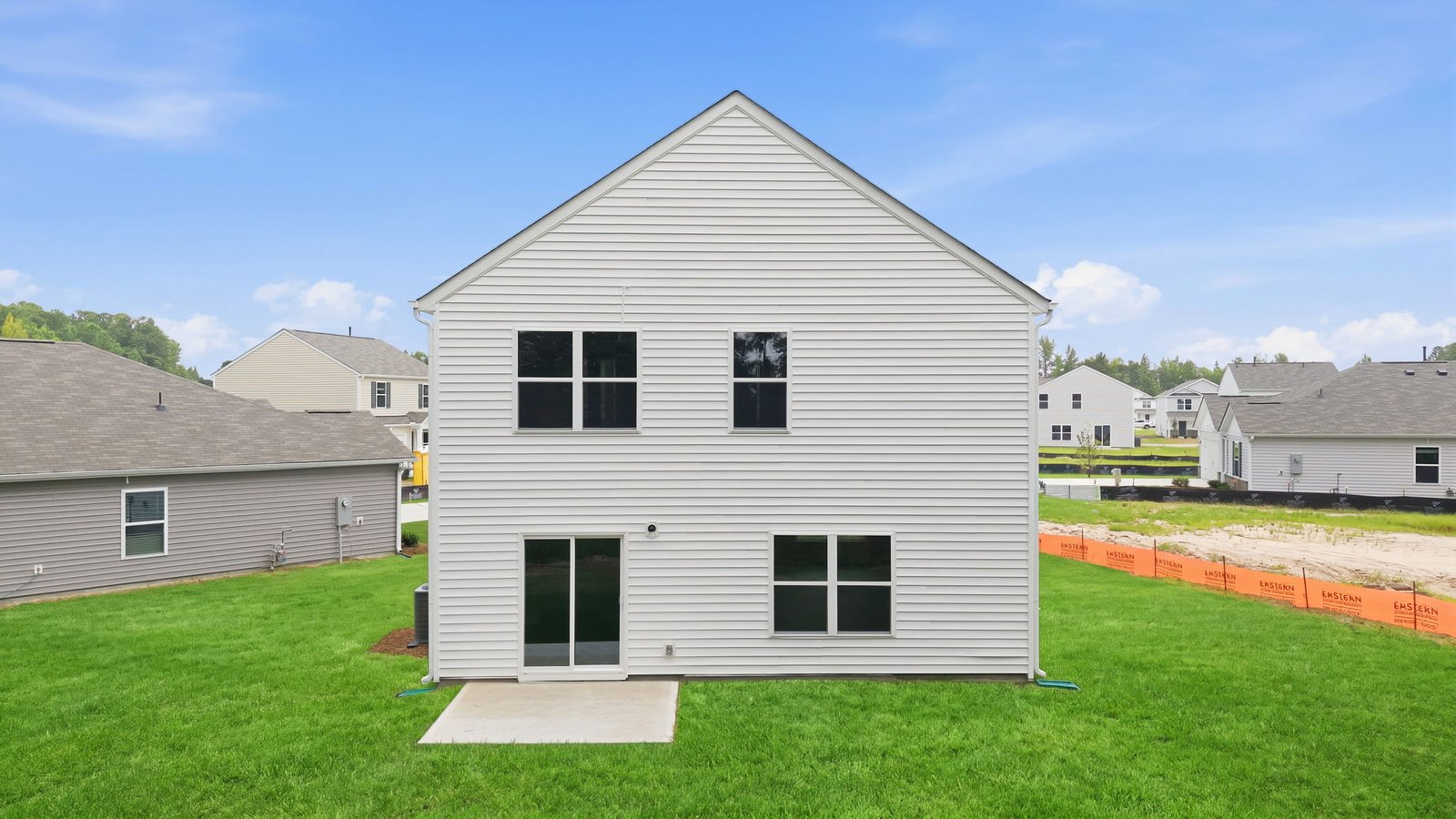 rear view of two story home with back patio pad