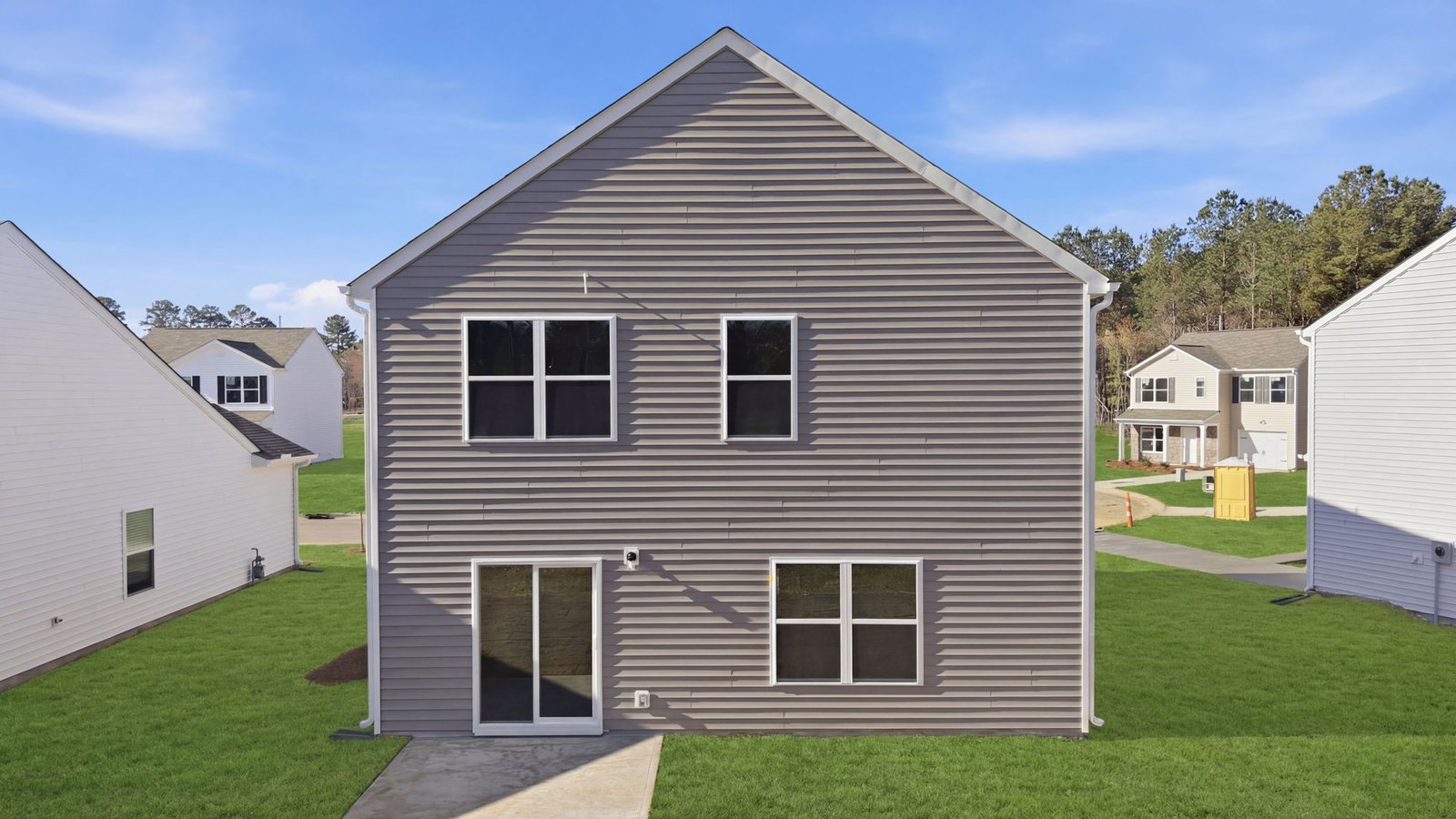 Rear view of the two story home with back patio pad