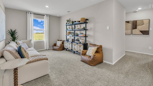 Gameroom off the staircase with carpeting and one window.