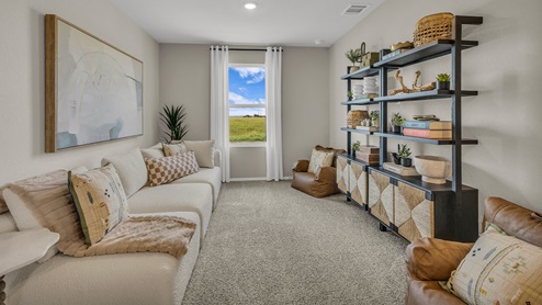 Gameroom off the staircase with carpeting and one window.