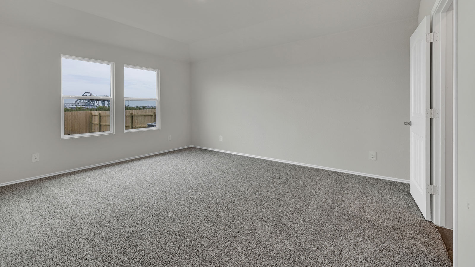 Main bedroom with carpeting and 2 windows.