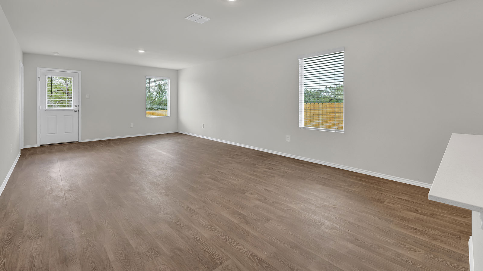 Living room with vinyl flooring, 2 windows, and  half lite exterior door.