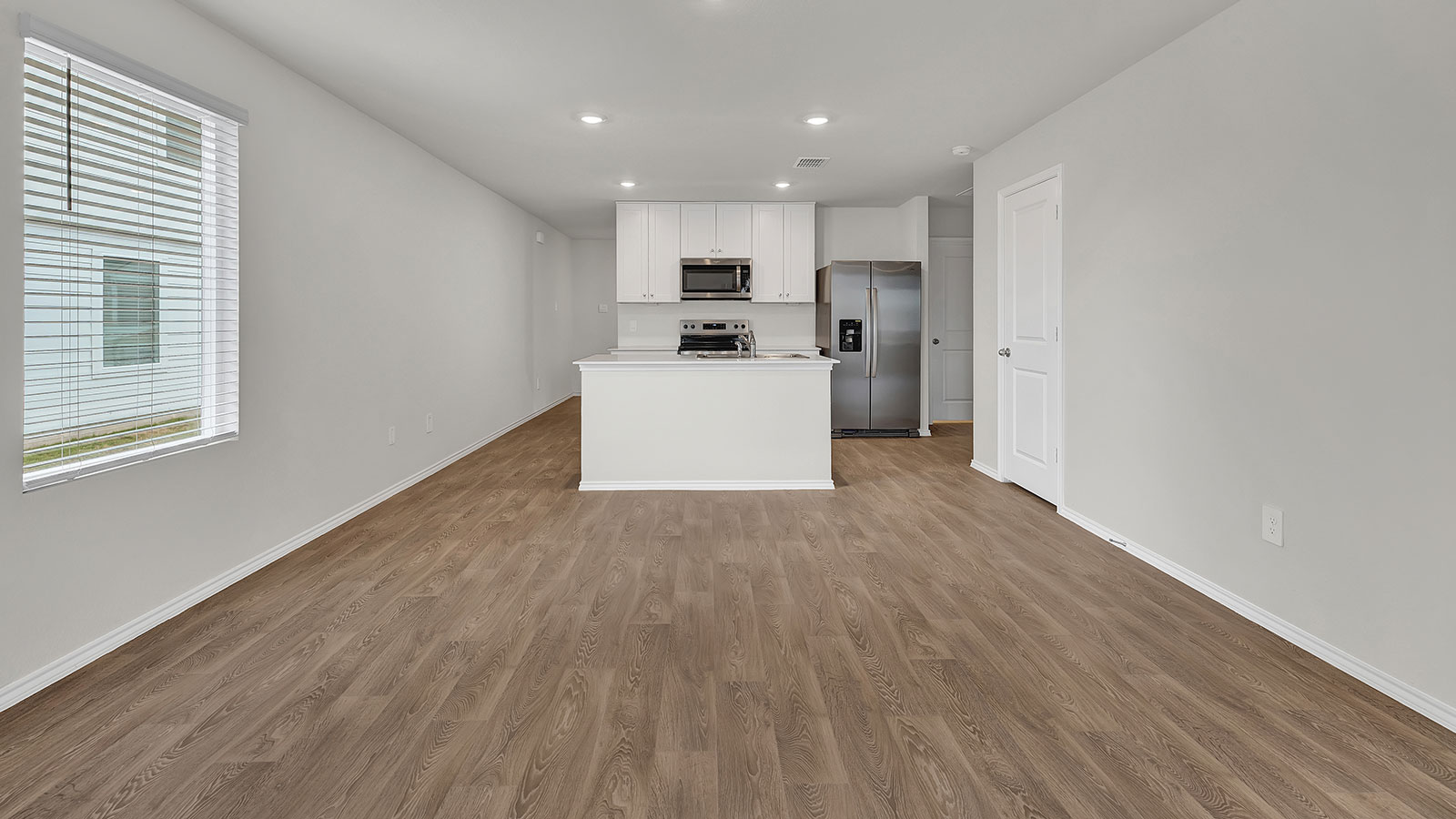 Living room with vinyl flooring, 2 windows, and  half lite exterior door.