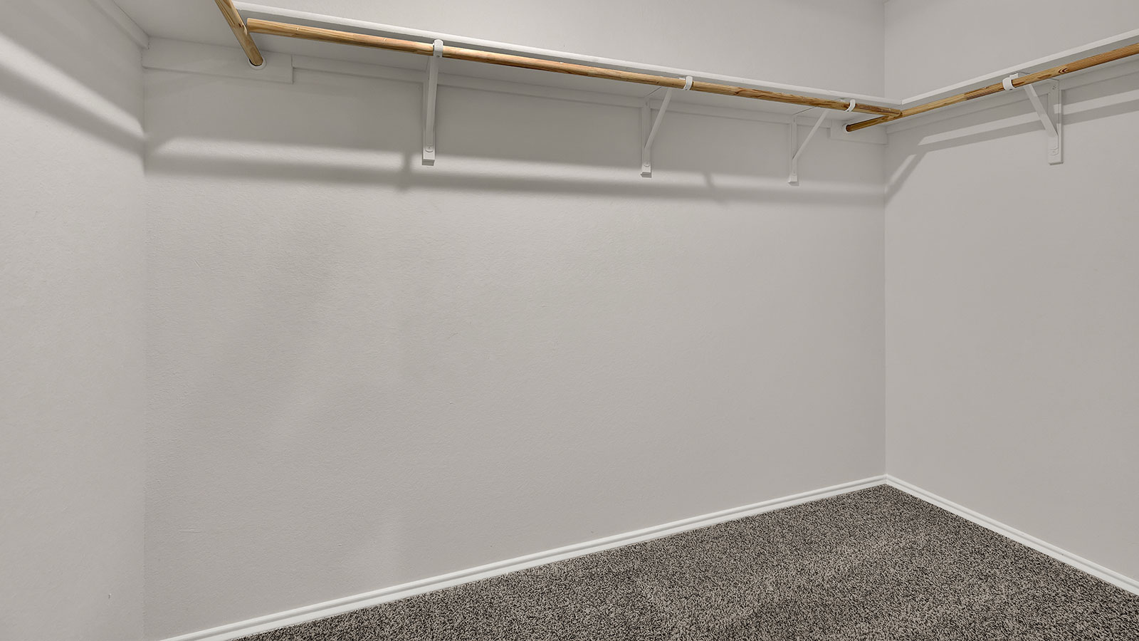 Main bedroom closet with carpeting and wooden shelving.