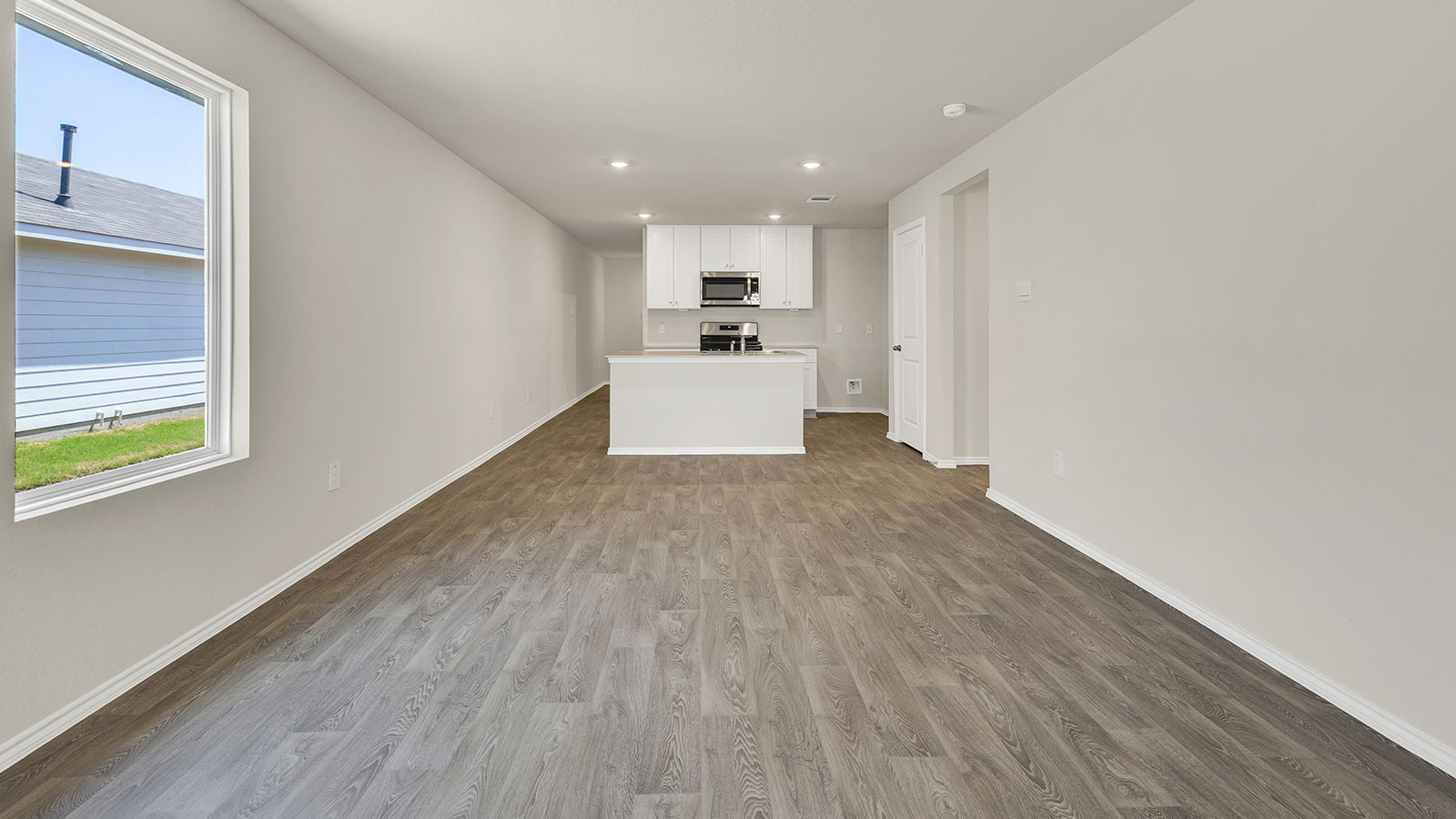 Living room with vinyl flooring, 2 windows, and  half lite exterior door.