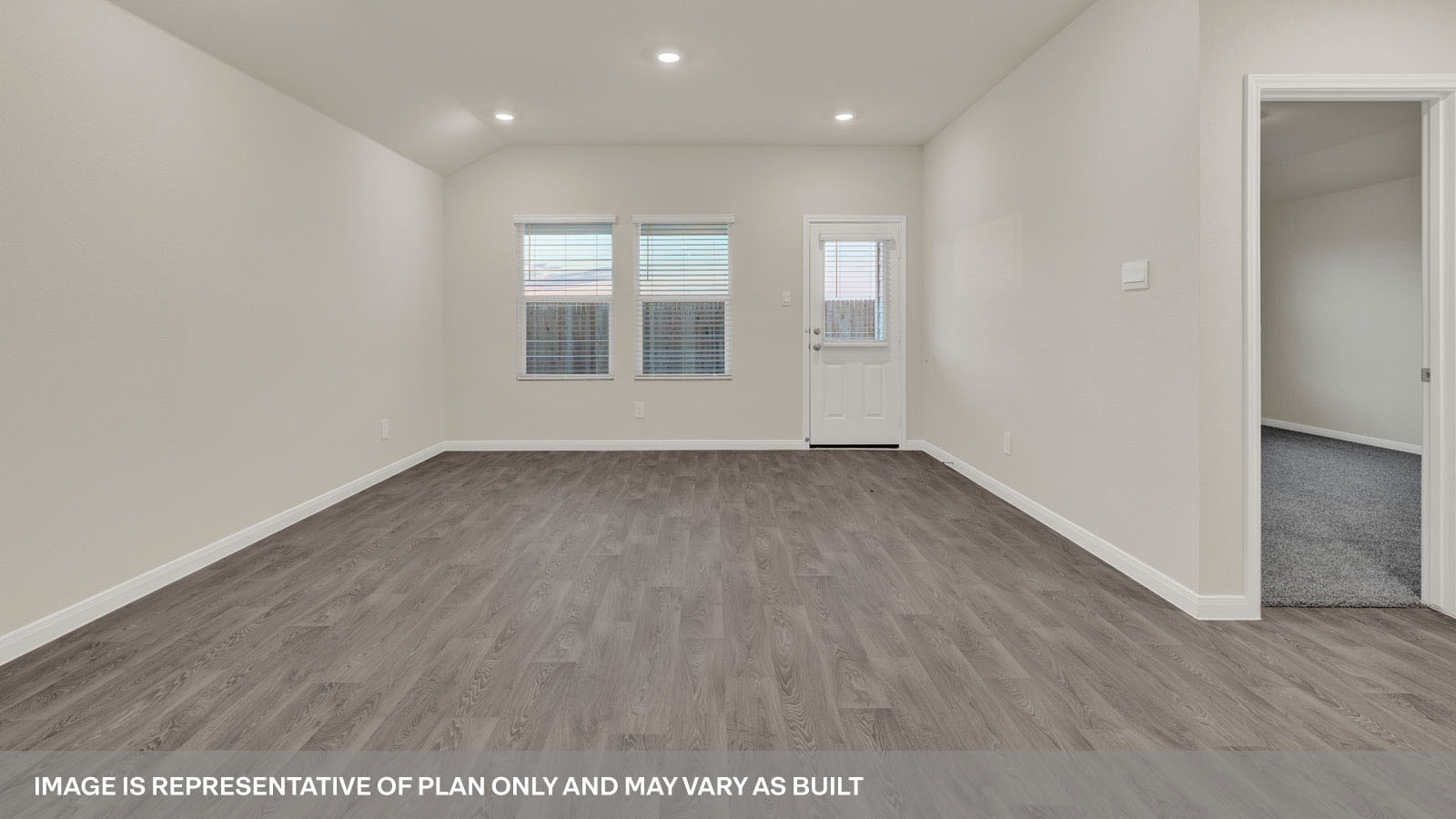 Spacious living room with brown flooring, beige walls and windows