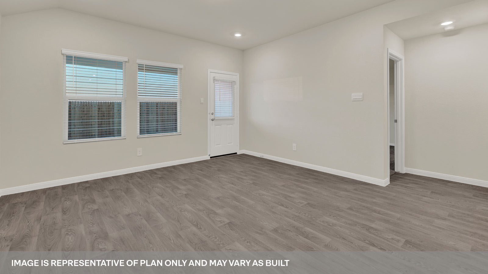 Spacious living room with brown flooring, beige walls and windows