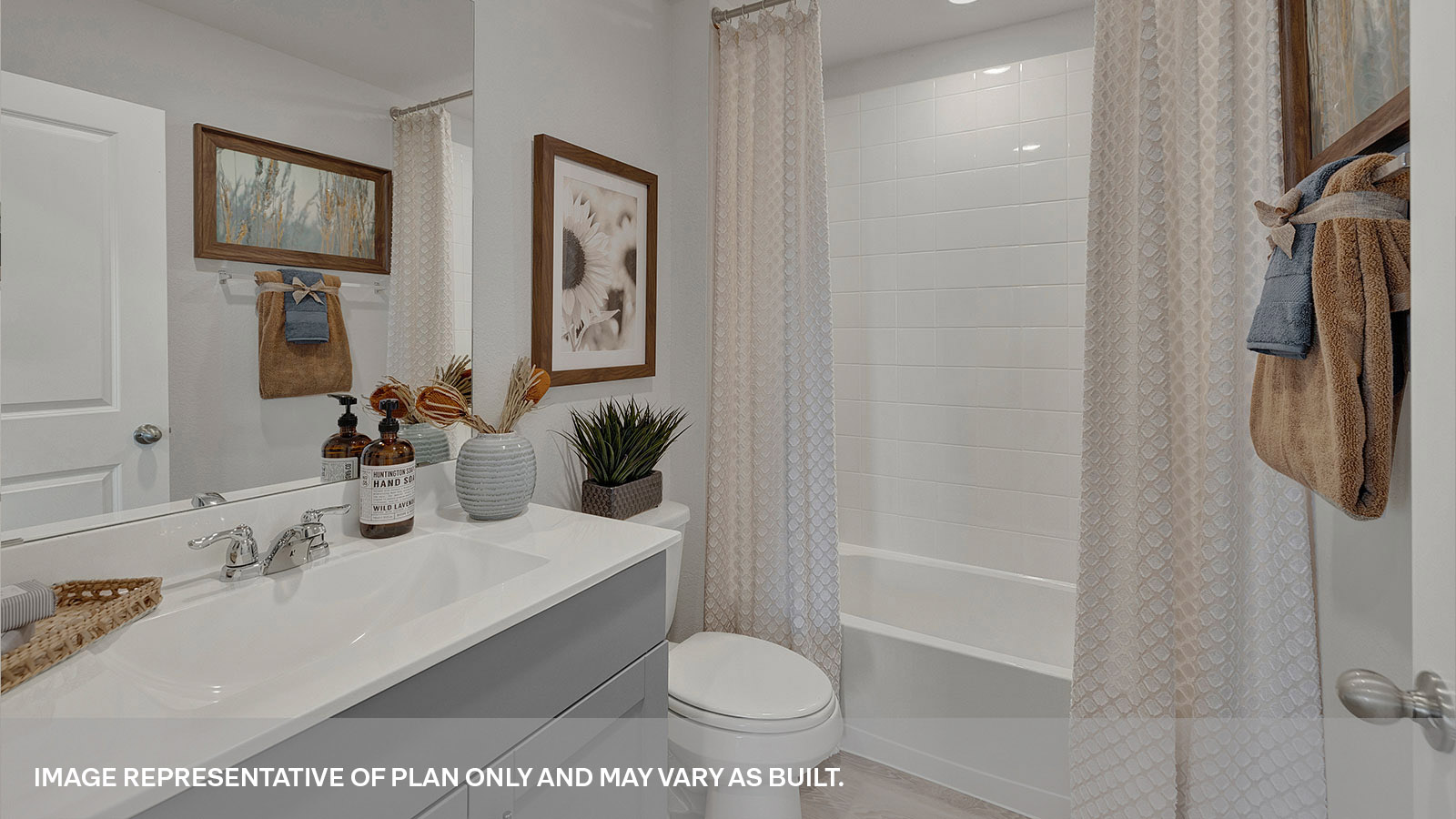 Hall bathroom with single sink vanity, toilet, and tub with tile surround.