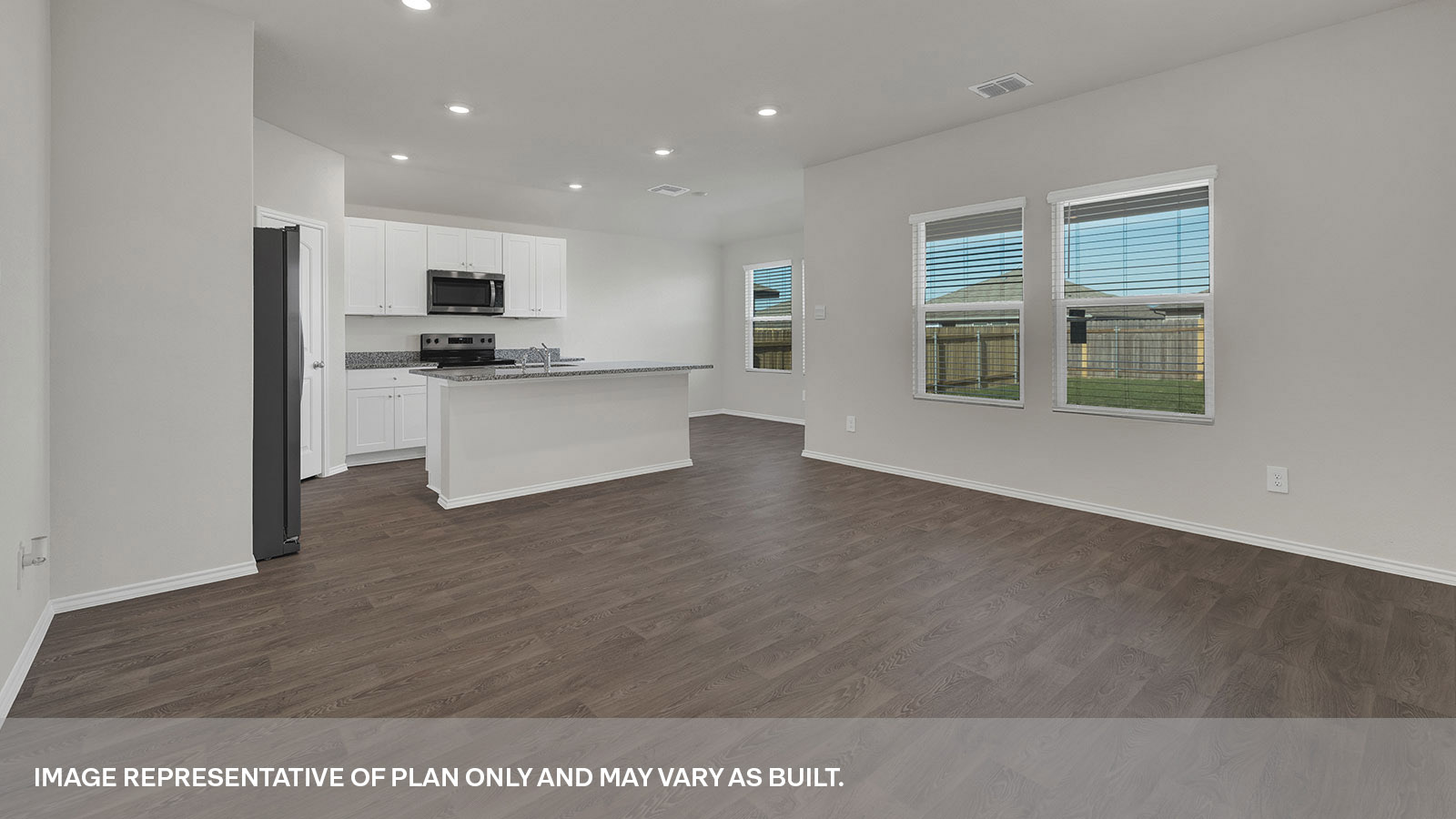 Kitchen with a kitchen island and large sink looking into the living room and 2 windows in the living room.