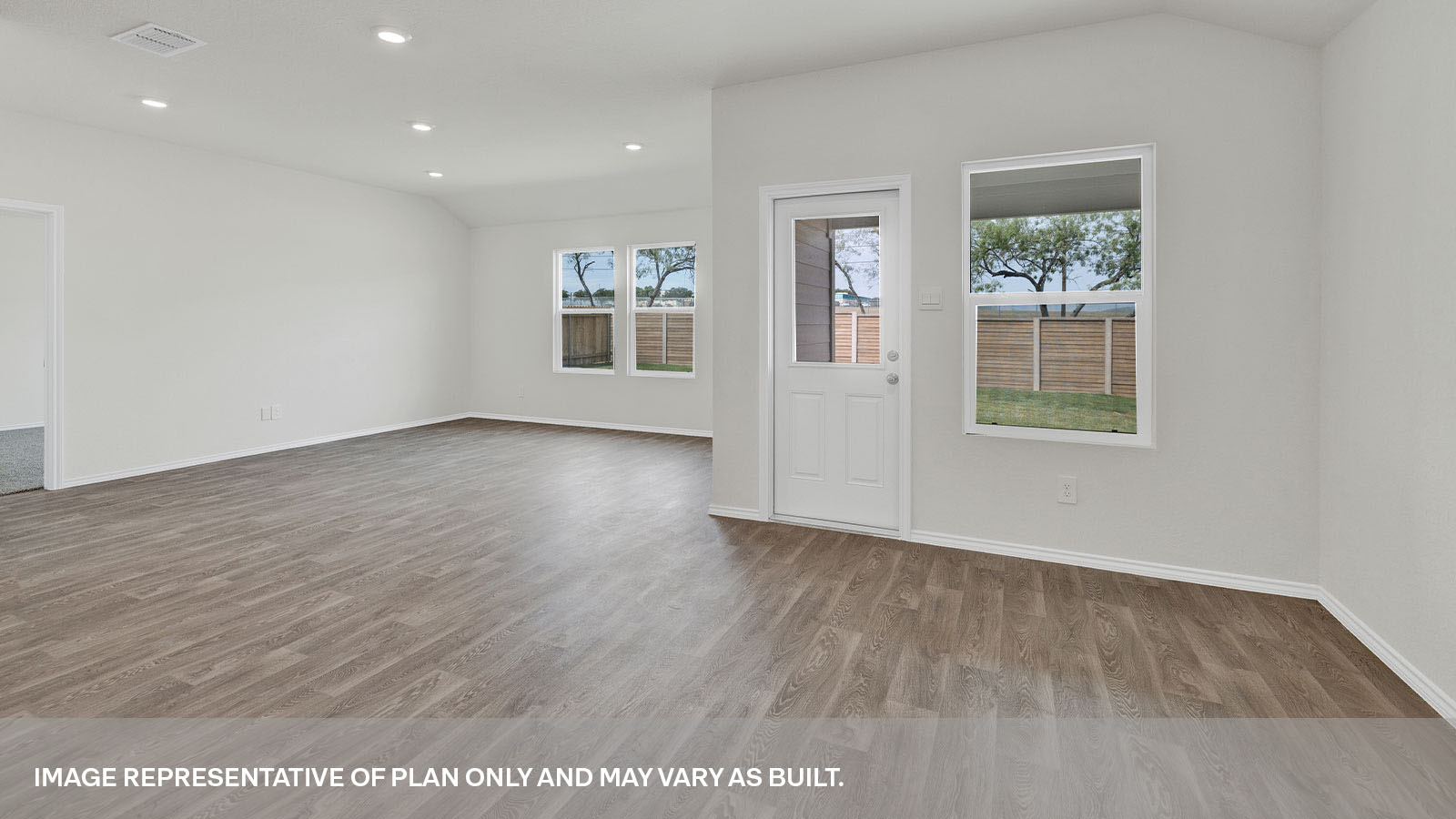Living room opening to the dining room with vinyl flooring, 3 windows, and a half lite exterior door.