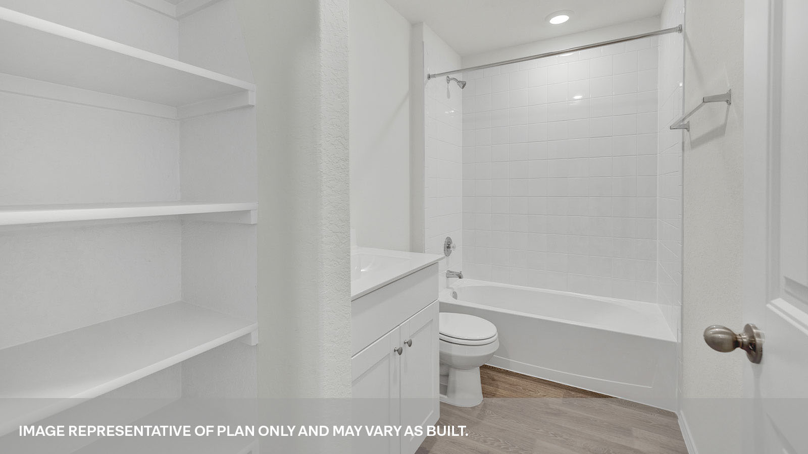 Bathroom with a tile surround shower/tub combo, single sink, wood shelf and white cabinets.