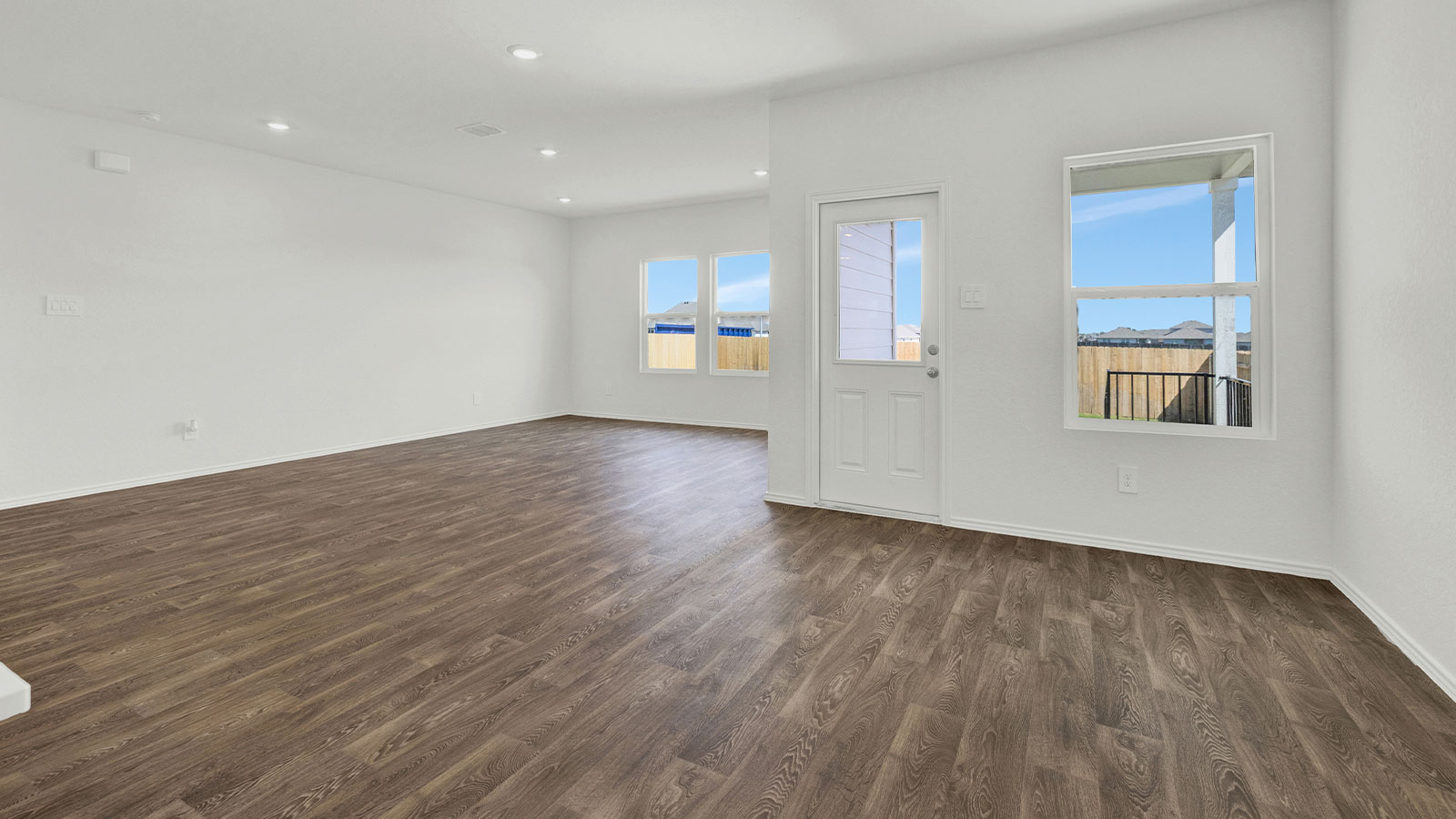 Dining room opening to the living room with vinyl flooring and windows.