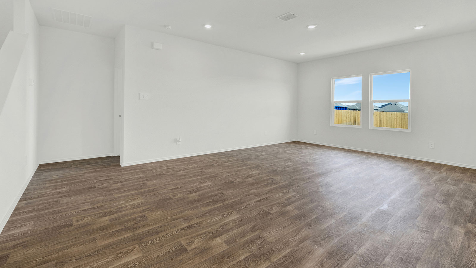 Living room with vinyl flooring, windows, and a half lite exterior door.
