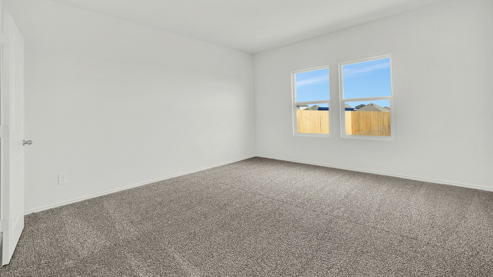 Main bedroom with carpeting and windows.