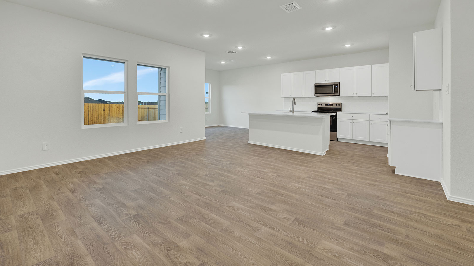 Living room with vinyl flooring and 2 windows.