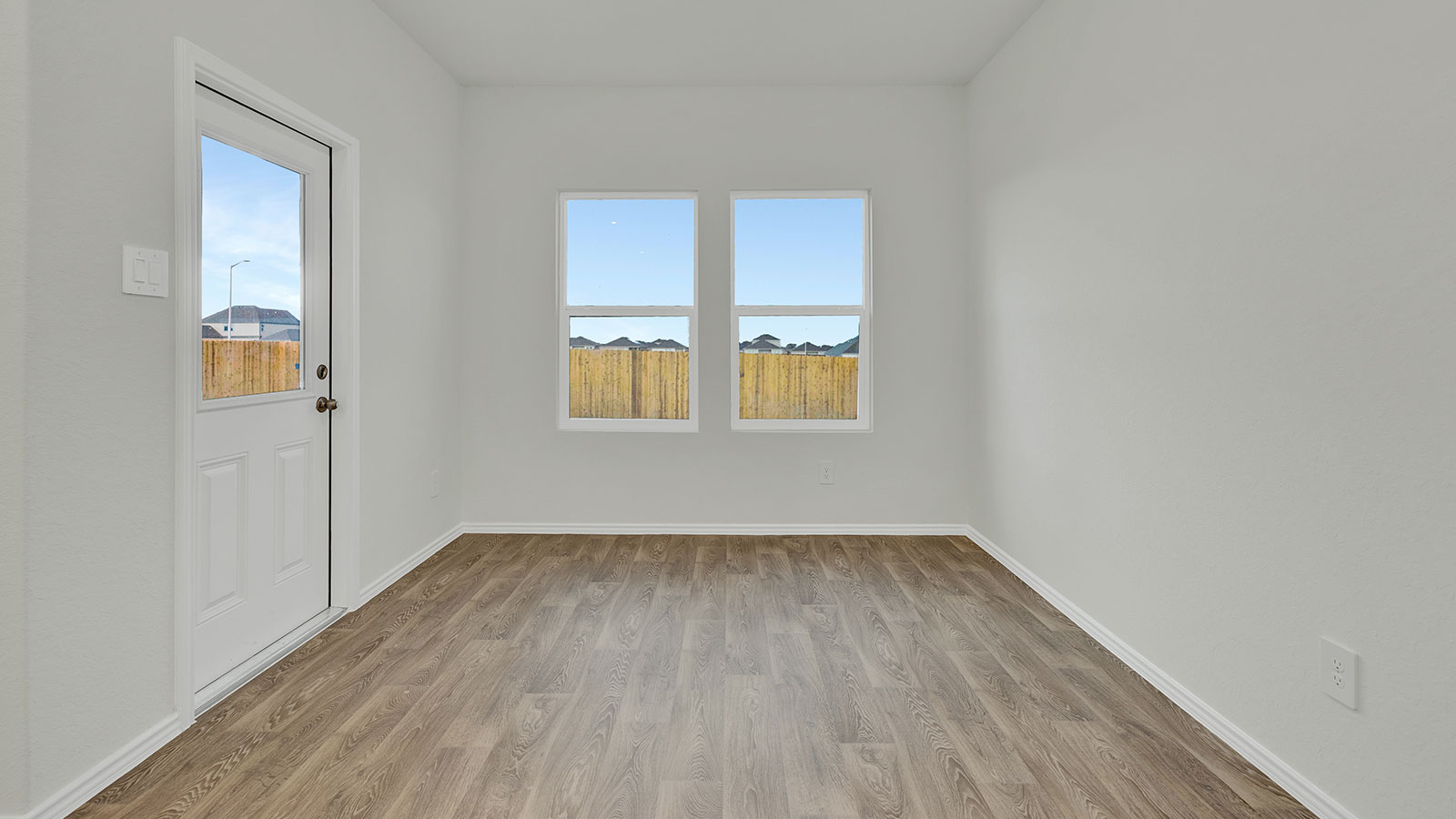 Dining room with vinyl flooring and two windows.