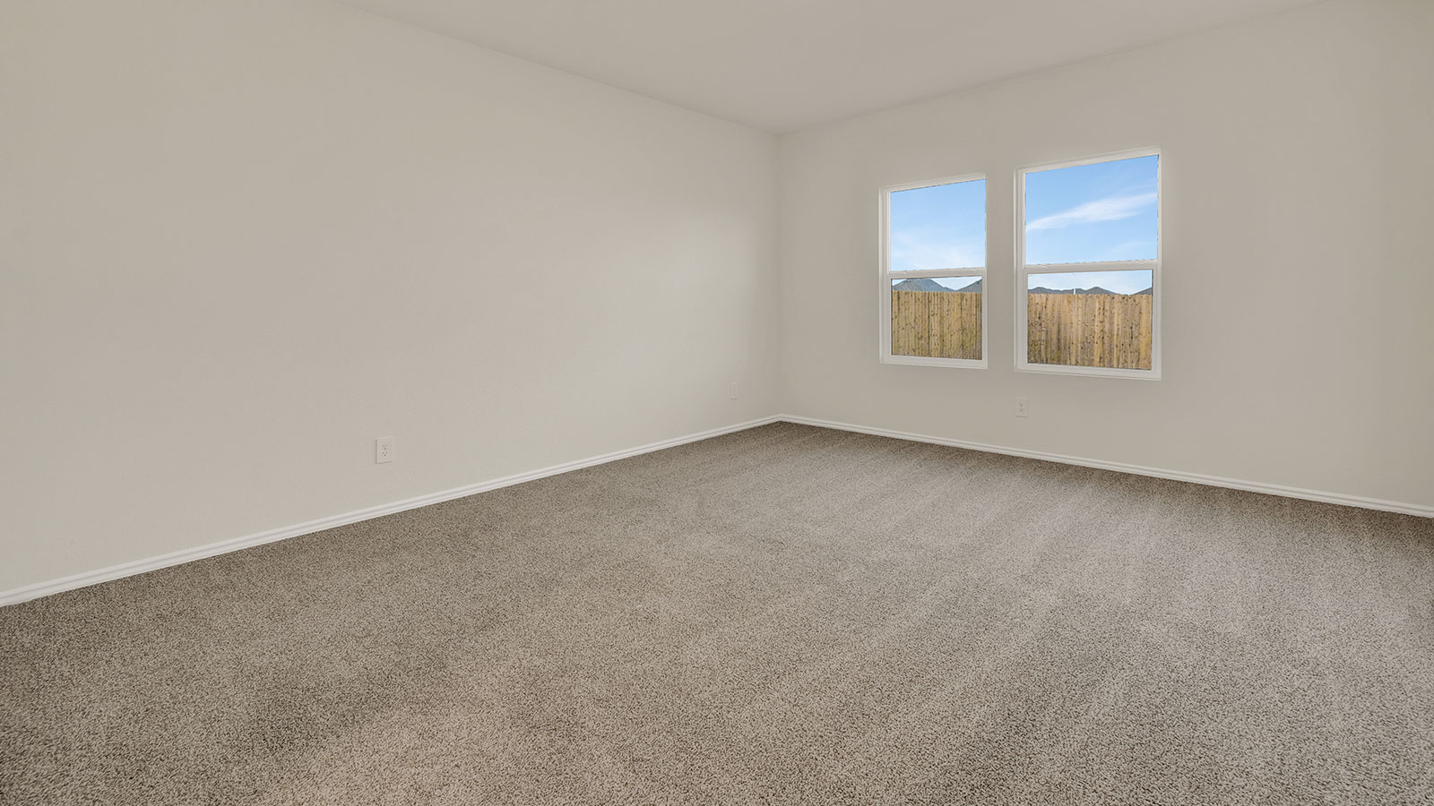 Main bedroom with carpeting and two windows.