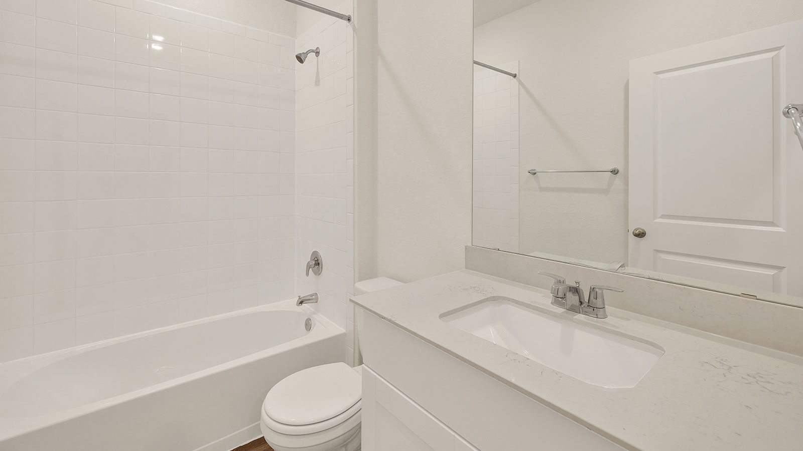 Hall bathroom with vanity, toilet, and tub with tile surround.