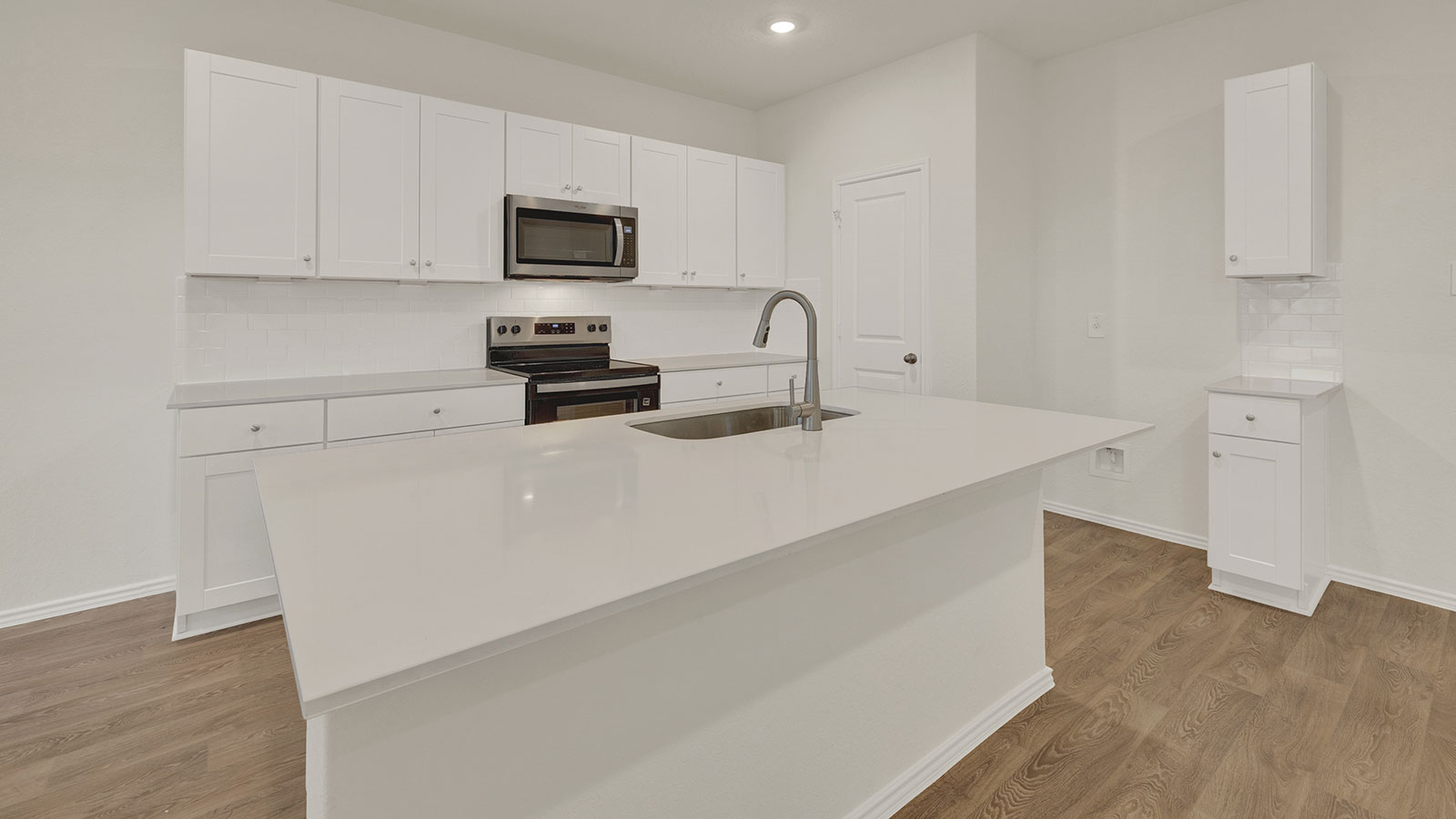 Kitchen with kitchen island, white cabinets, and quartz countertops.