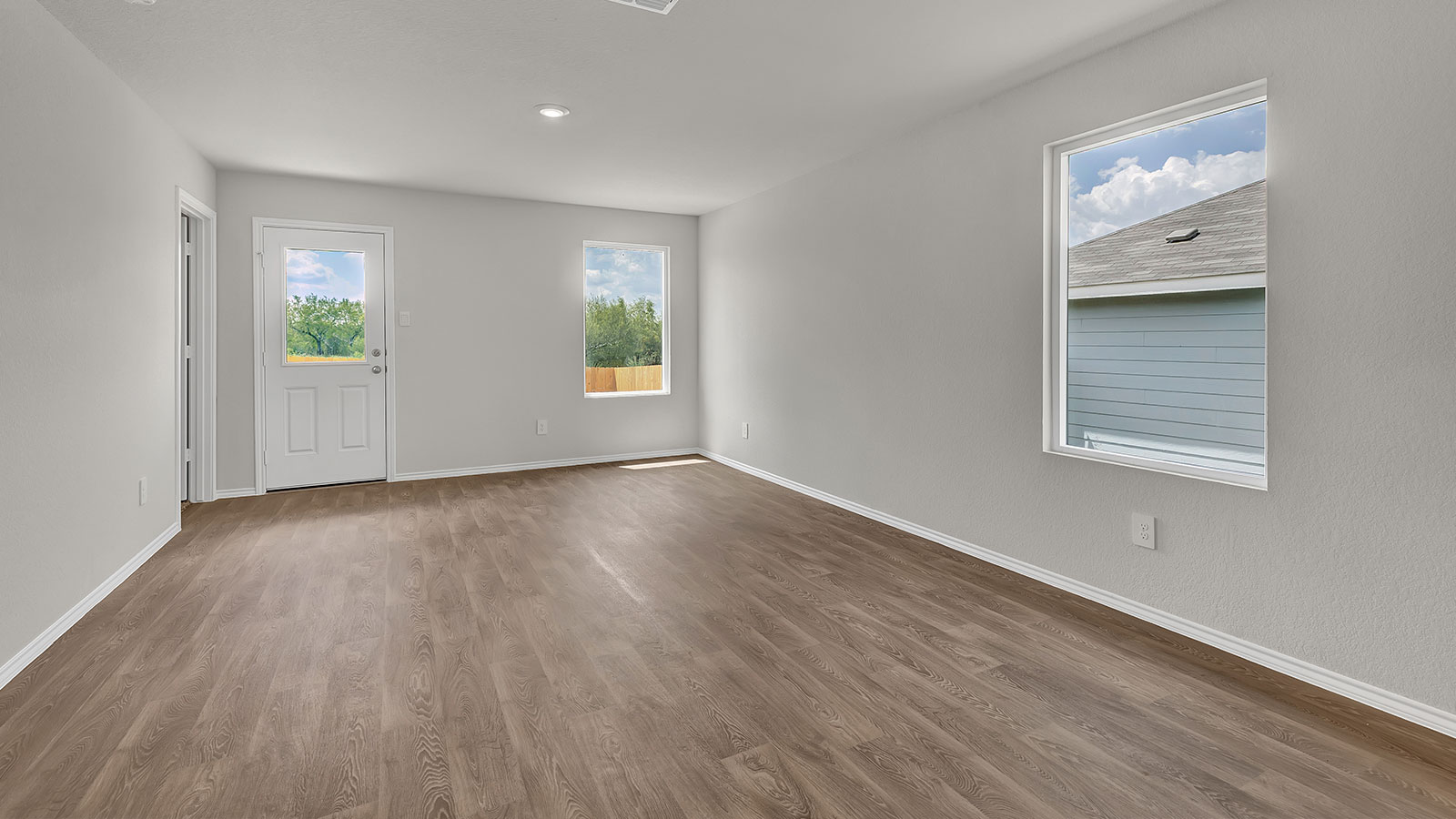 Dining room and living room with vinyl flooring, 2 windows, and a half lite exterior door.
