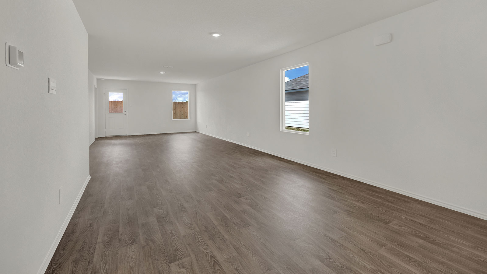 Living room with vinyl flooring, 2 windows, and  half lite exterior door.