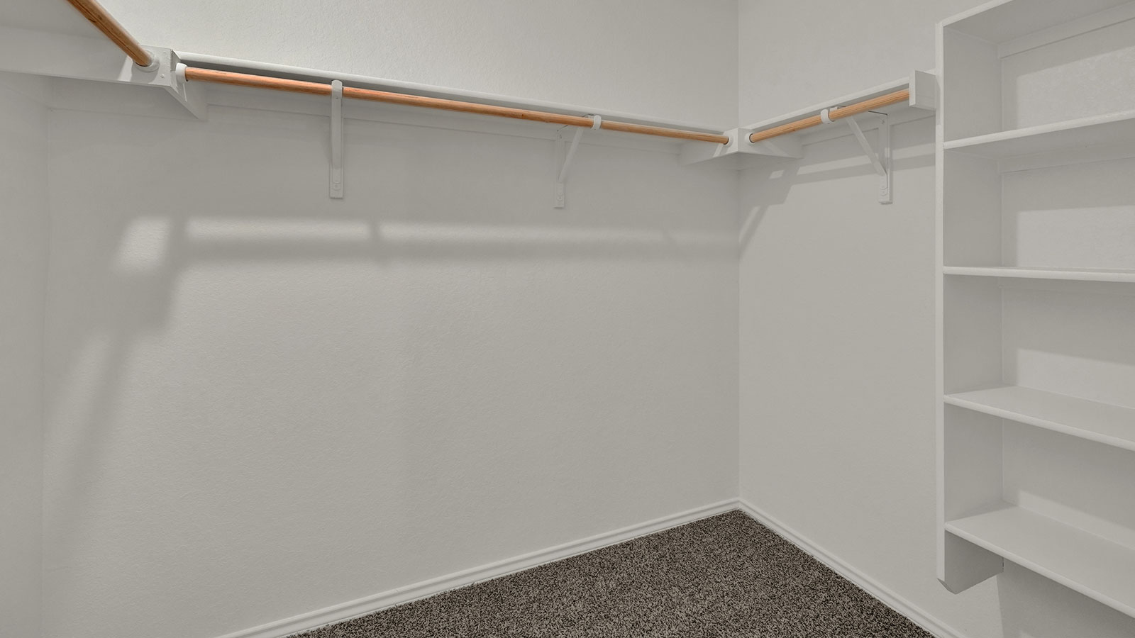 Main bedroom closet with carpeting and wooden shelving.