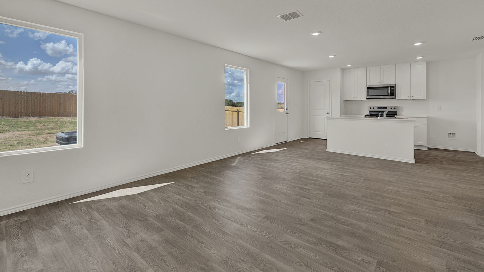 Living room with vinyl flooring opening to the kitchen.