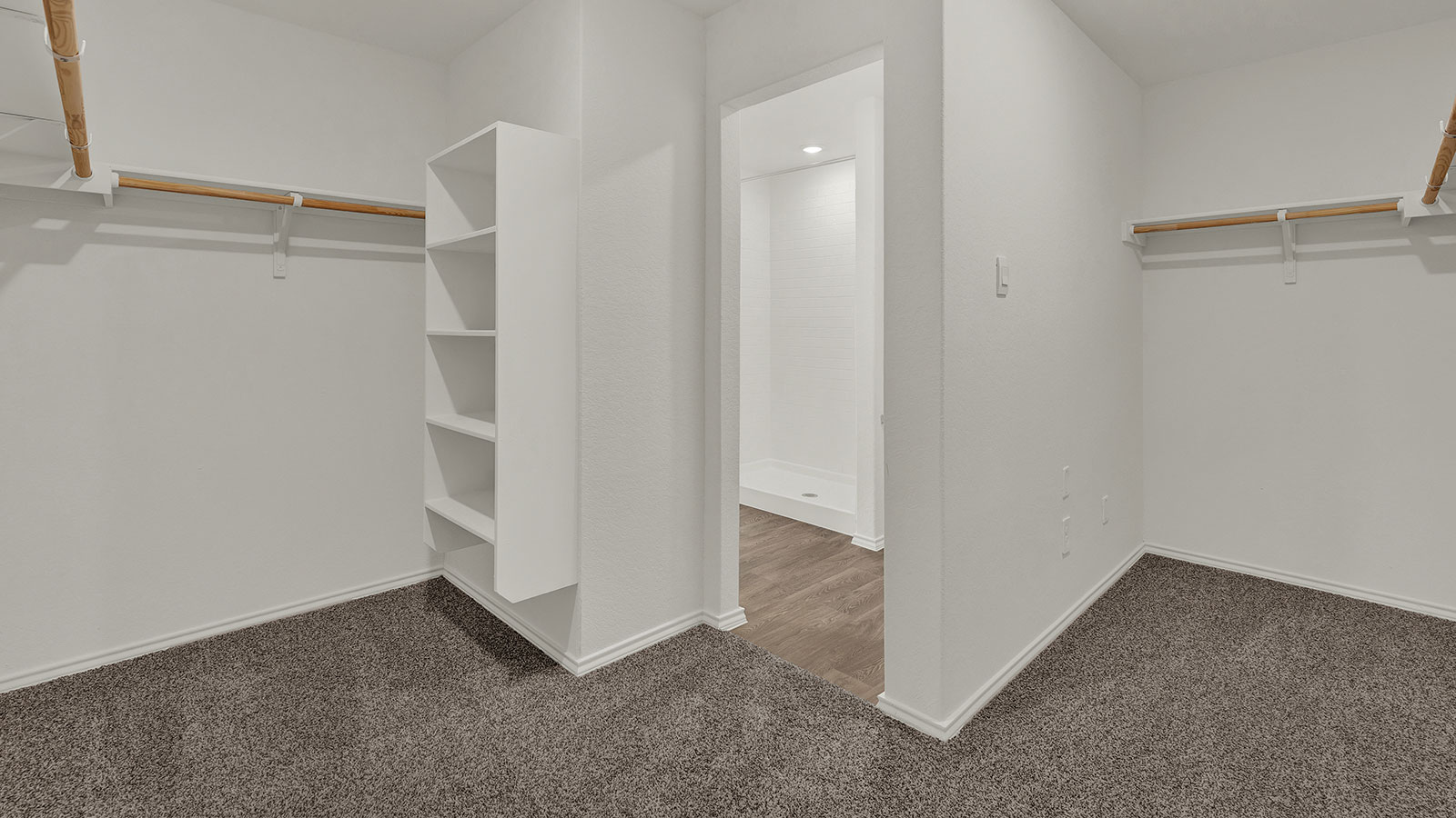 Main bedroom closet with carpeting and wooden shelving.