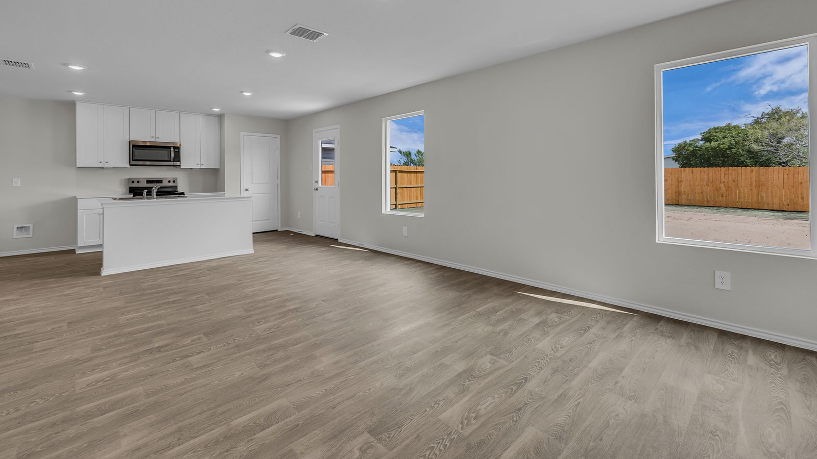 Living room with vinyl flooring opening to the kitchen.