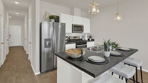 Kitchen with kitchen island with white cabinets and entry hallway.