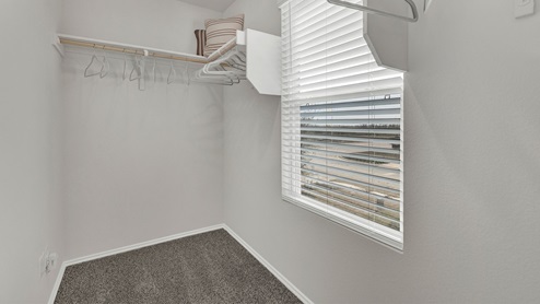 Large walk-in closet with wooden shelves and window.