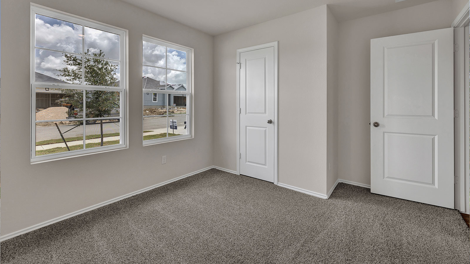 Front bedroom with carpeting and two windows.