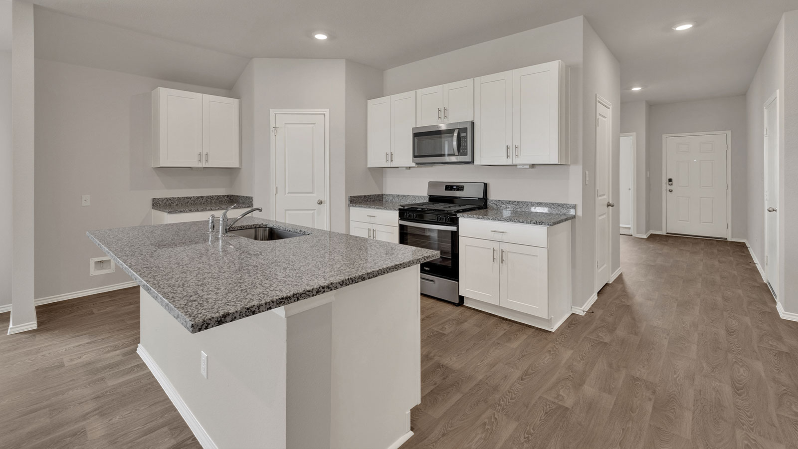 Kitchen with white cabinets and entry hallway.