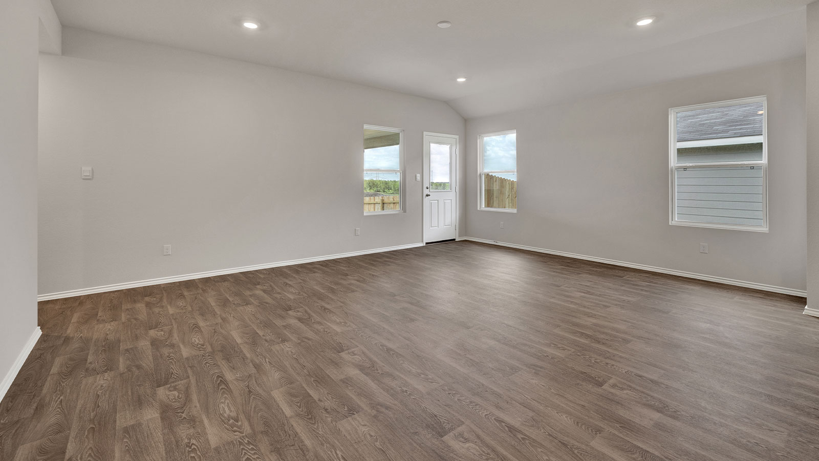 Living room with vinyl flooring and two windows.