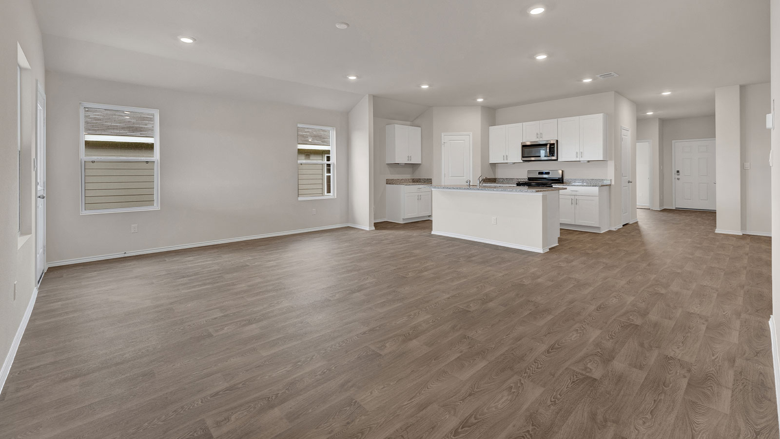 Living room with vinyl flooring and two windows.