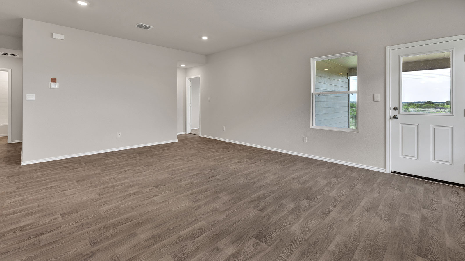 Living room with vinyl flooring and two windows.
