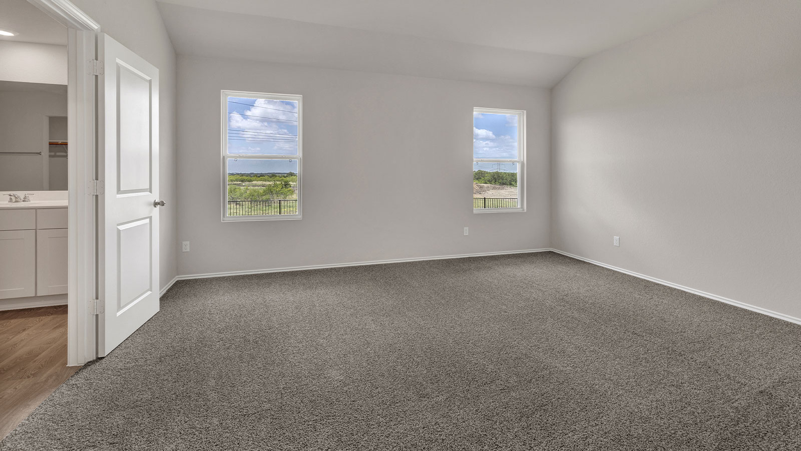 Main bedroom with carpeting and two windows.