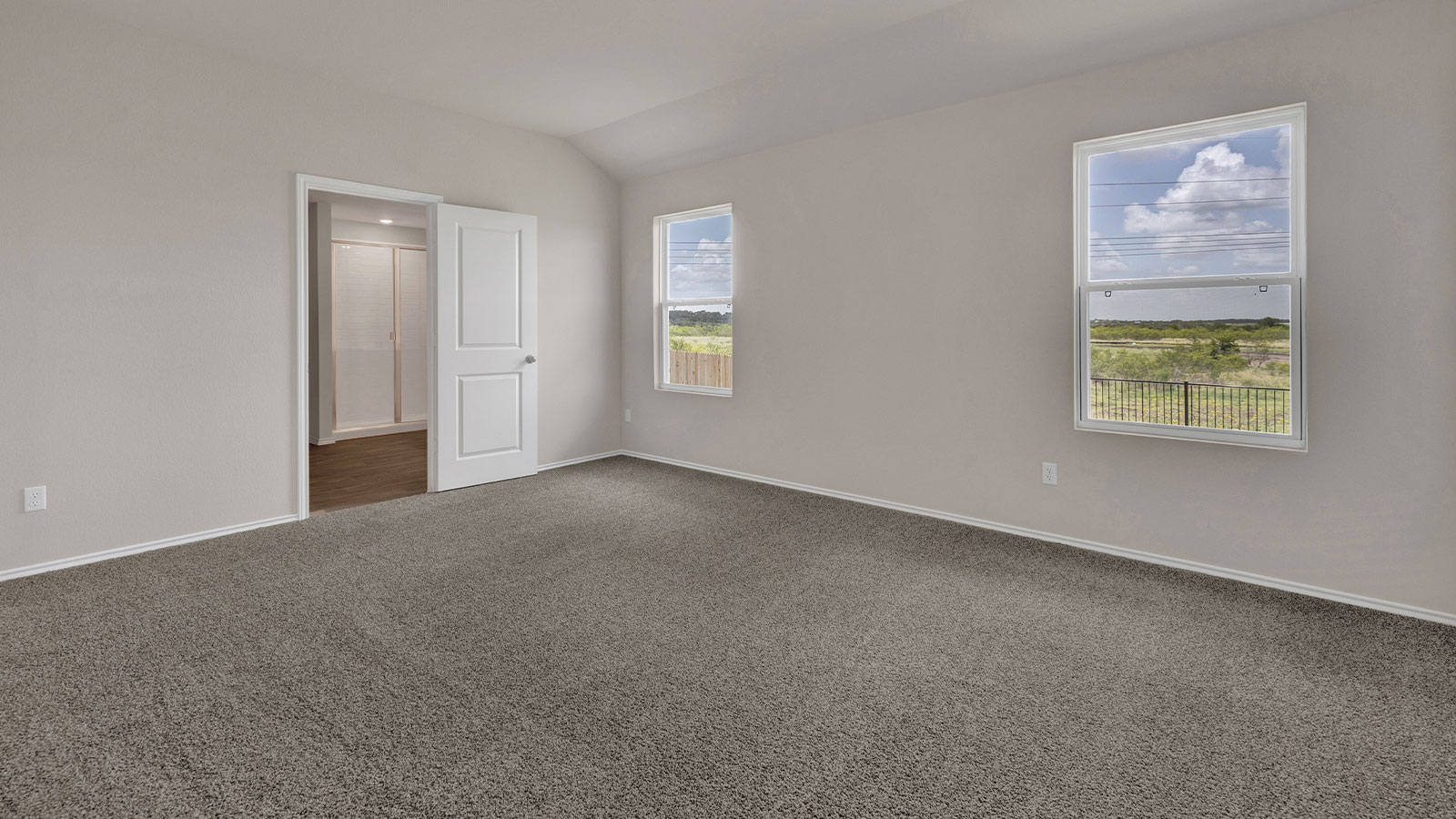 Main bedroom with carpeting and two windows.