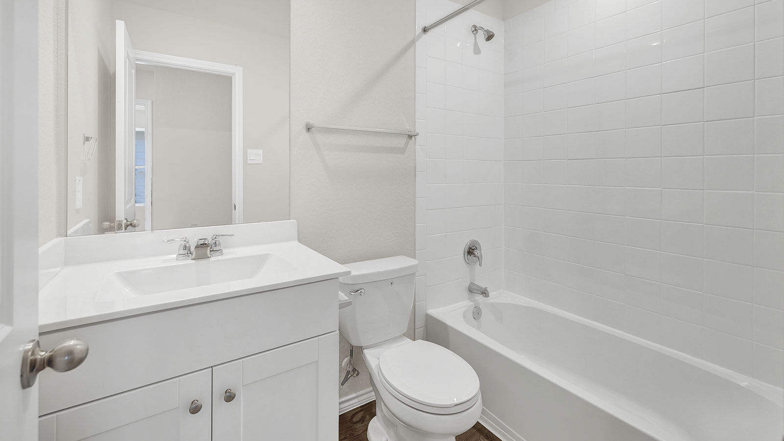 Hall bathroom with single-sink vanity, toilet, and tub with tile surround.