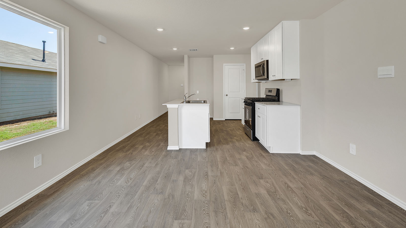 Dining room and living room with vinyl flooring, 2 windows, and a half lite exterior door.