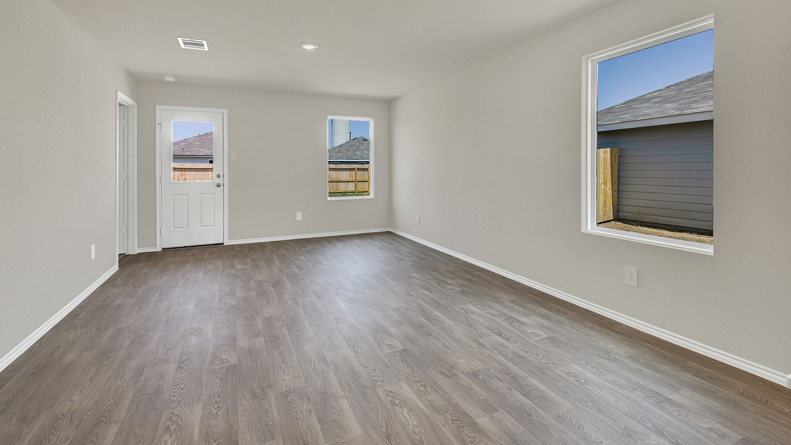 Living room with vinyl flooring, 2 windows, and a half lite exterior door.