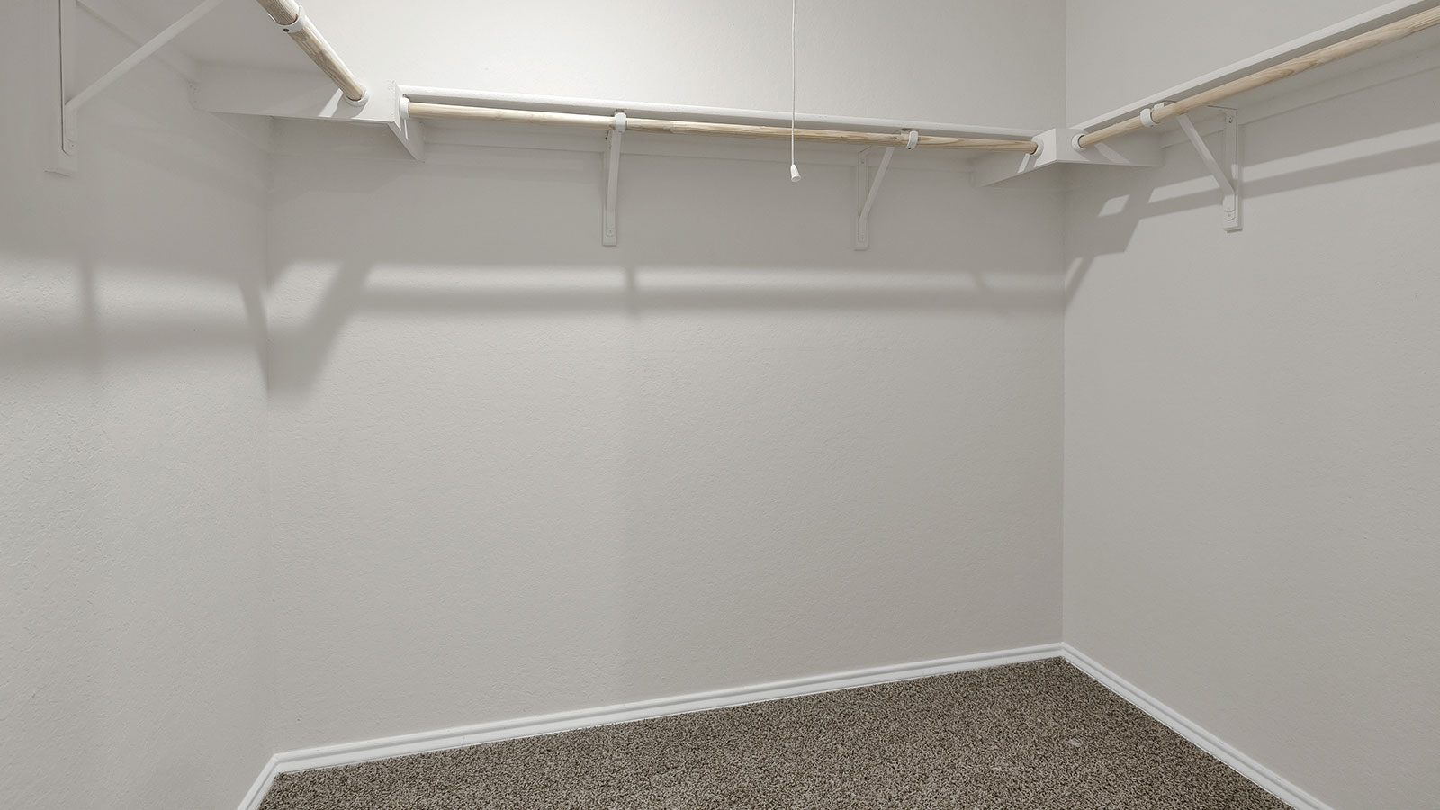 Main bedroom closet with carpeting and wooden shelving.