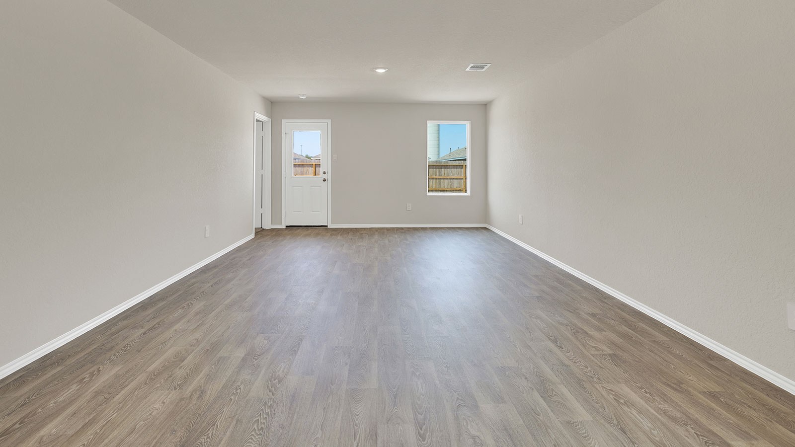 Living room with vinyl flooring, 2 windows, and  half lite exterior door.